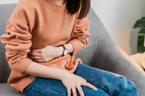 Žena trpící bolestí žaludku, drží si břicho