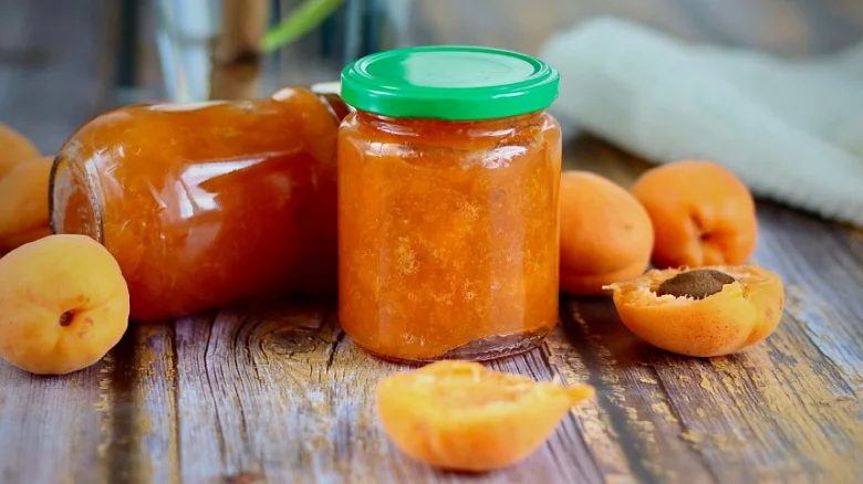Skleněné lahvičky s meruňkovou marmeládou a čerstvé meruňky