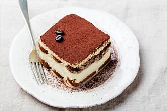 Kousek tiraみsu na talíři s kávovými zrnky