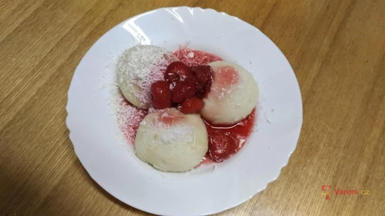 Kynuté jahodové knedlíky na talíři s práškem cukru