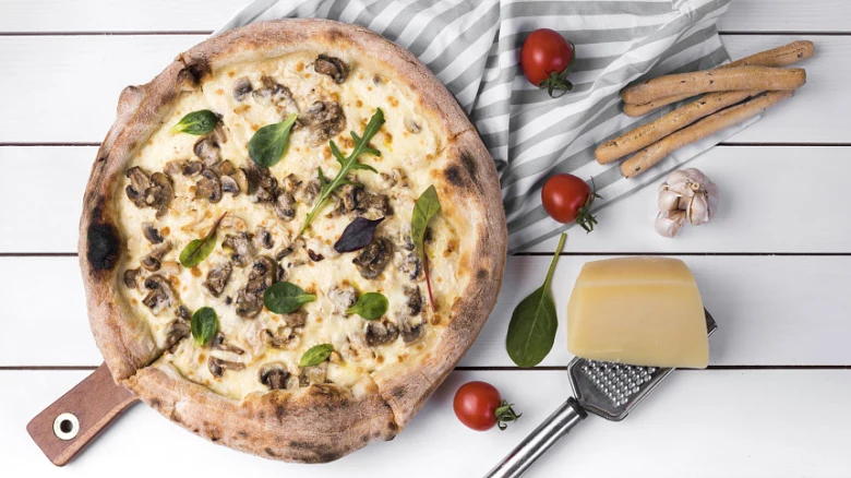 Pizzová půlka s smetanovou omáčkou a houbami na dřevěném podkladu
