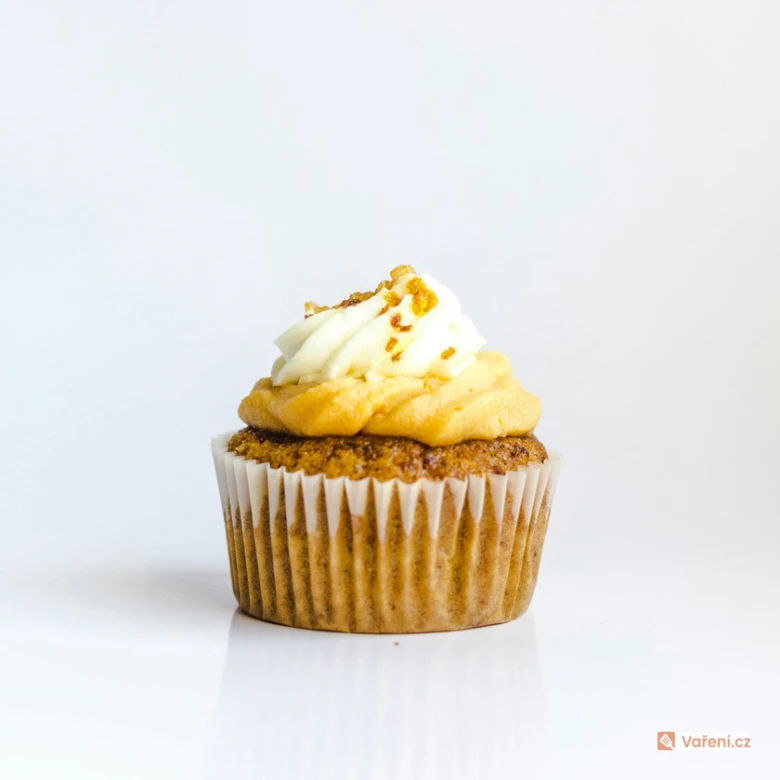 Cupcake s bílým krémem a kousky sušenky na vrcholu