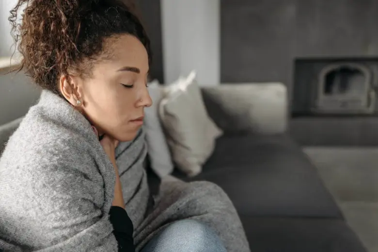Žena s rukou na krku, zjevně trpící pocitem knedlíku v krku