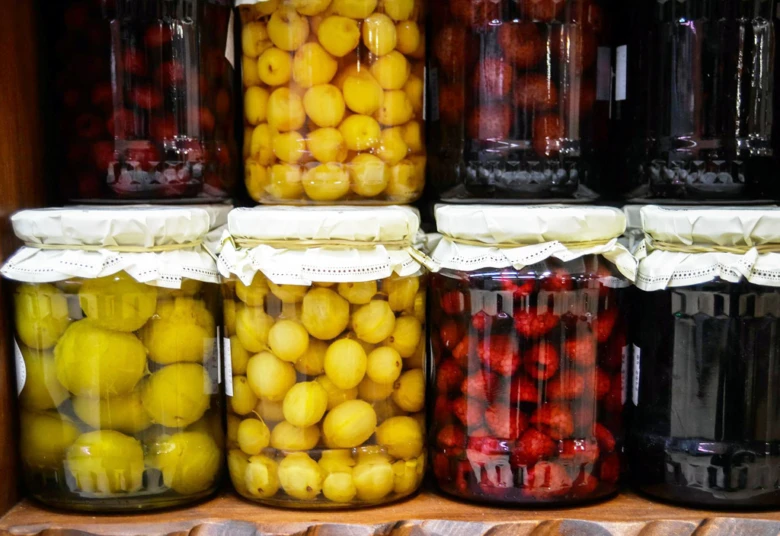 Skleněné lahve s konzervovanými ovoce jako švestky a maliny