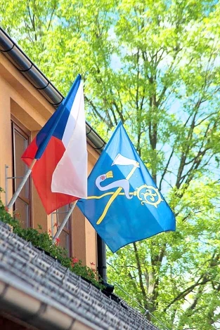 Česká vlajka a městská vlajka na domě v zeleném prostředí
