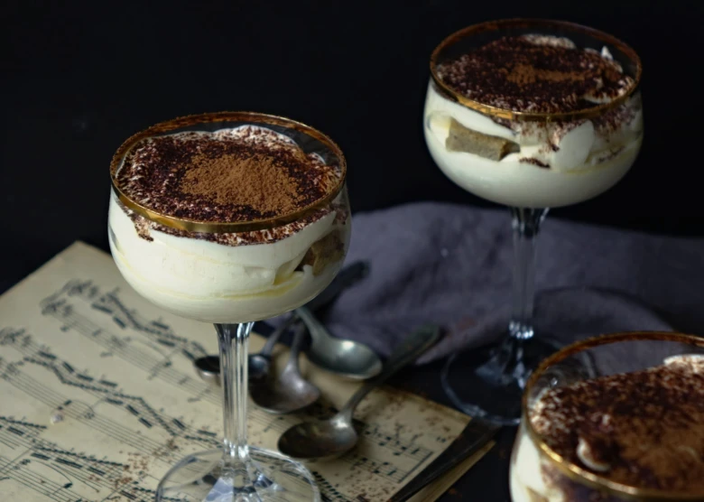 Tiramisu ve skleničkách s kakaovým práškem na tmavém pozadí