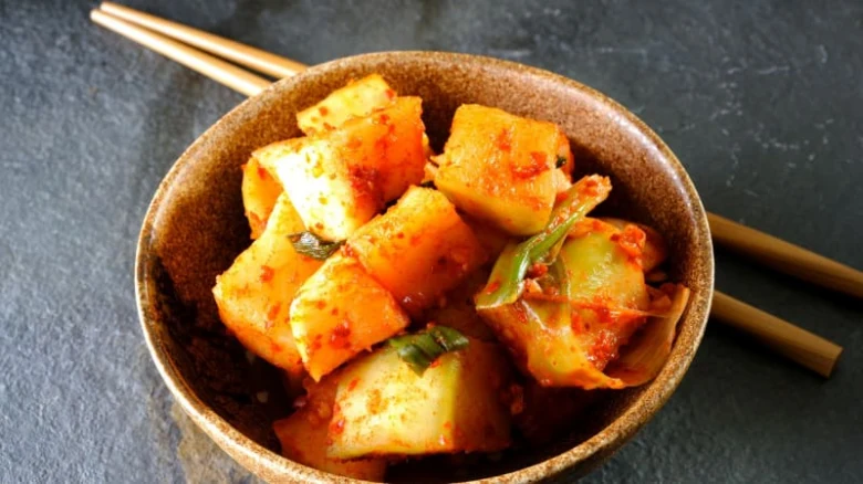 Kimchi v hnědém hrnci s bambusovými hůlkami