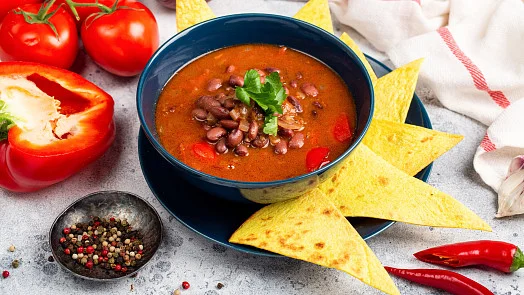 Čočková polévka v modré mísce s koriandrem a nachos