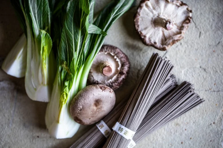 Suroviny pro ramen: čerstvé zeleninové listy, houby a tmavé nudle