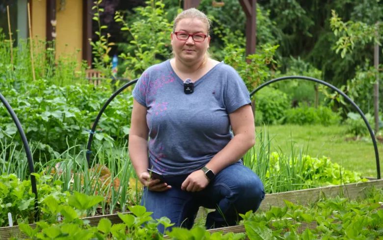 Žena v zahradě u zvýšeného záhonu s rostlinami