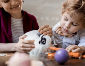 Žena s dítětem hraje s králíkem na stole