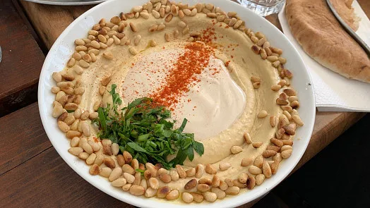 Hummus s piniovými oříšky a bylinkami na talíři