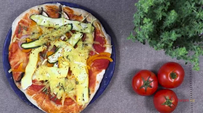 Pizza s smetanovou omáčkou a zeleninou na modrém talíři