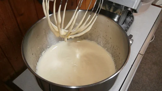Bílá těstová směs v kovovém míchacím hrnci s přívěskem na mixér