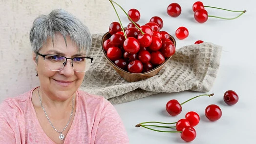 Čerstvé třešně v dřevěné mísce na bílém podkladu.