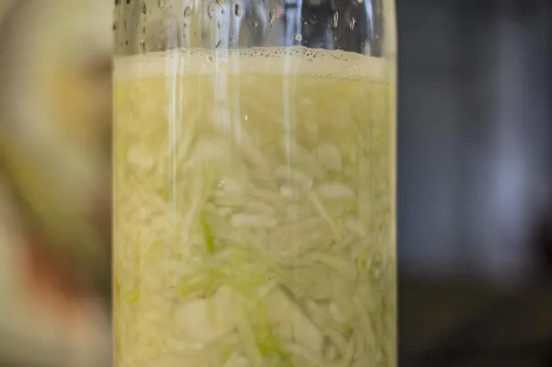 Fermentující zelí v sklenici s pěnou a bublinami