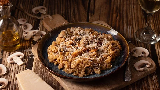 Rizoto s houbami a parmezánem na dřevěném stole