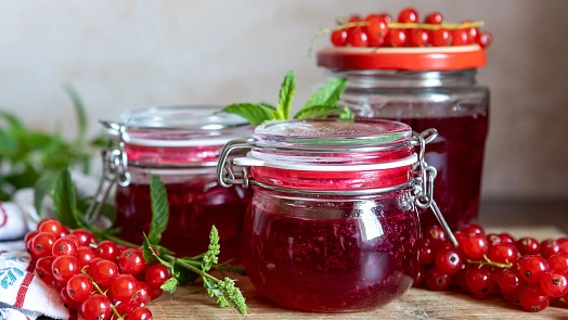 Skleněné lahvičky s rybízovou marmeládou a čerstvými bobulemi