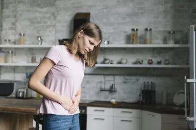Žena v kuchyni drží břicho, trpí křečemi v břiše
