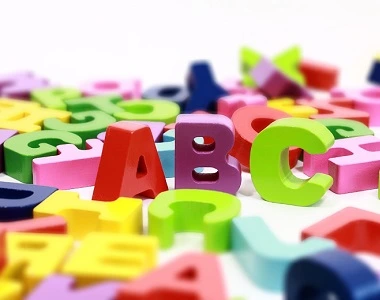 Kolorované plastické písmena ABC na bílém pozadí.