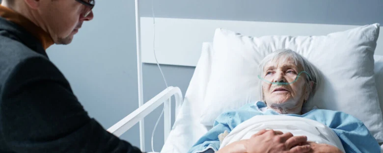 Elderly woman in hospital bed with oxygen mask being comfort