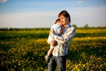 Father holding child in field
