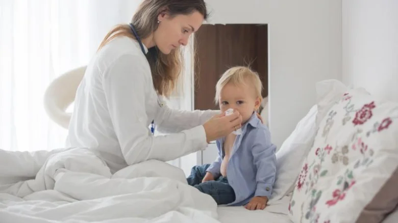 Lékařka vyšetřuje dítě s možným problémem na mandlích.