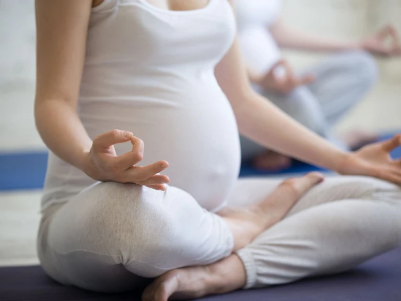 Těhotná žena v meditaci se připravuje na narození dítěte.