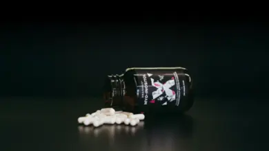 Fialová lahvička s inositolem a bílé tobolky na tmavém pozadí.