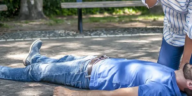 Muž leží na zemi po pití alkoholu v parc