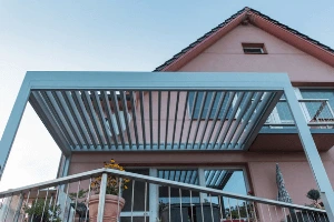 Moderní kovová pergola nad terasou s výhledem na dům.