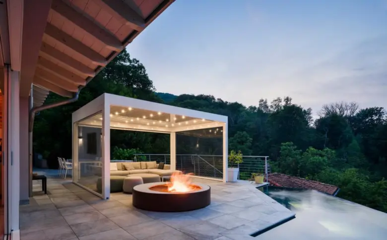 Moderní bílá pergola s ohništěm na terase v západním slunci.
