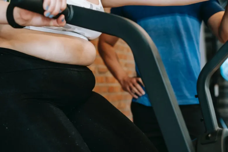 Osoba cvičí na fitness stroji v posilovně.