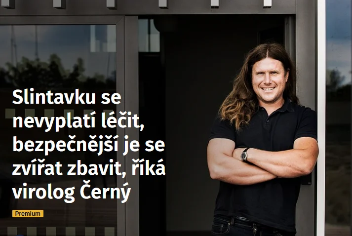 Muž s dlouhými vlasy stojí v dveřích budovy.