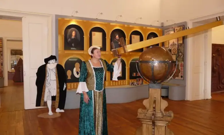 Žena v historickém kostýmu u astronomického globusu.