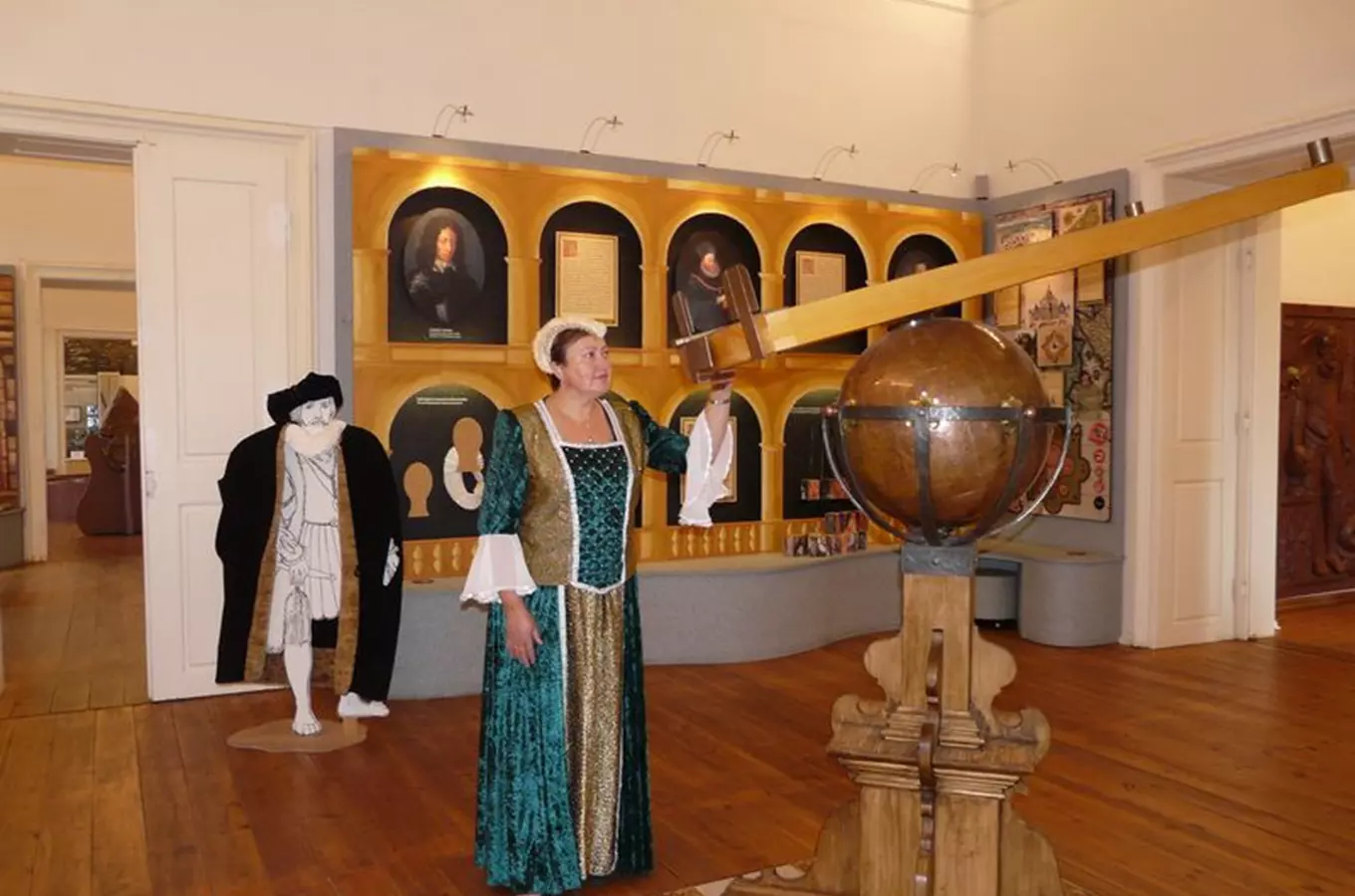 Žena v historickém kostýmu u astronomického globusu.