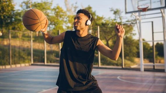 Muž hraje basketbal venku s náušnicemi.
